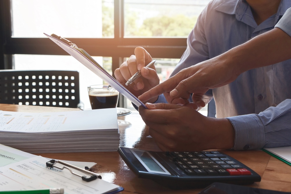 Kalkulator, dokumenty i monety na biurku symbolizujące ukryte koszty związane z działką